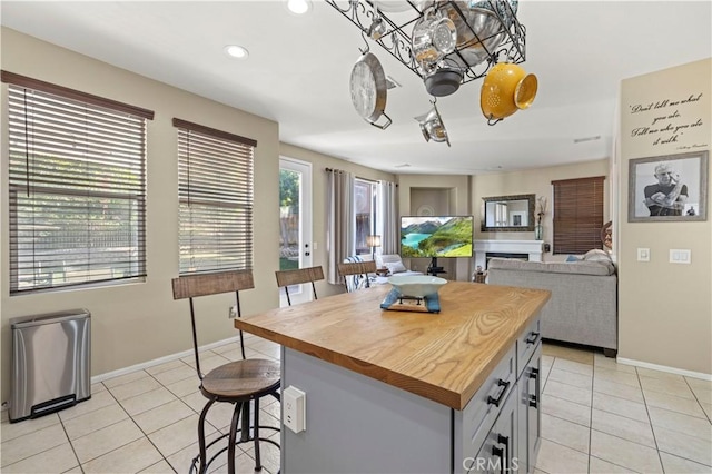 kitchen featuring gray cabinetry, a kitchen bar, a kitchen island, and light tile patterned floors