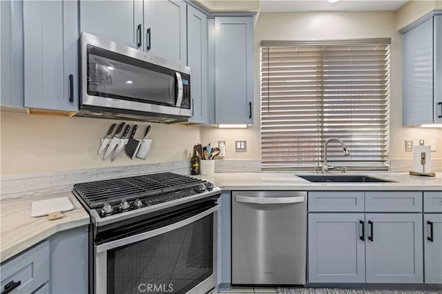 kitchen featuring stainless steel appliances, sink, and light stone counters