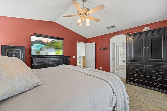 carpeted bedroom featuring lofted ceiling, ceiling fan, and ensuite bath