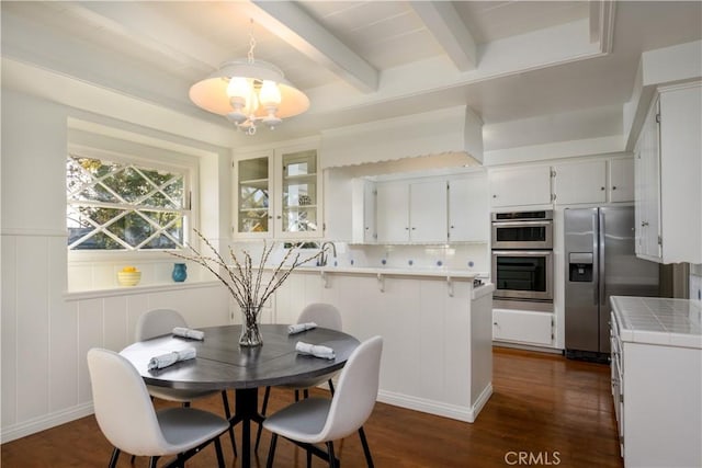 dining room with dark hardwood / wood-style flooring, sink, a chandelier, and beamed ceiling