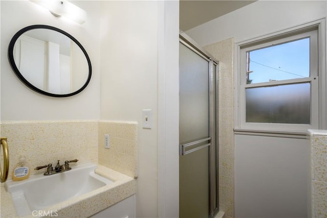 bathroom with an enclosed shower, sink, and backsplash