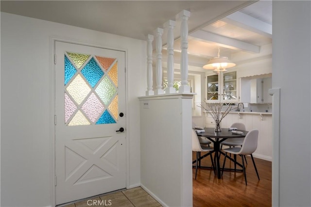 doorway to outside with tile patterned floors, beam ceiling, and sink