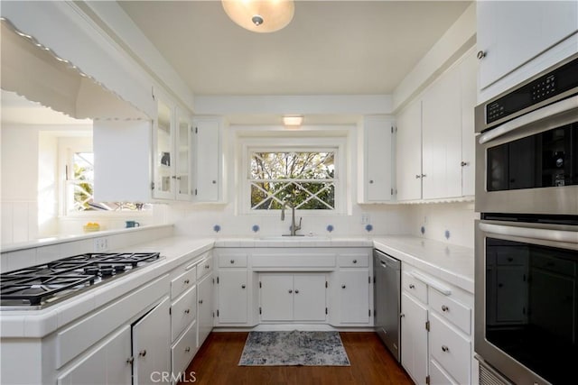 kitchen with appliances with stainless steel finishes, sink, white cabinets, and plenty of natural light