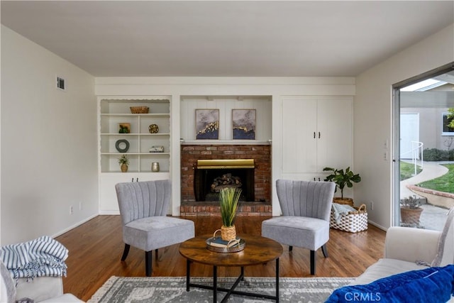 living room featuring a fireplace, built in features, and dark hardwood / wood-style floors