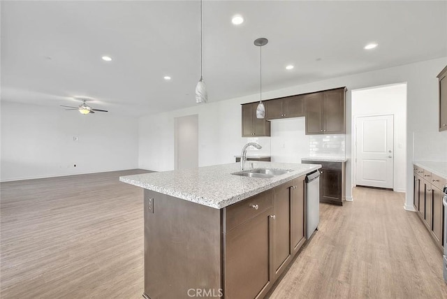 kitchen featuring sink, decorative light fixtures, light hardwood / wood-style flooring, dishwasher, and a kitchen island with sink