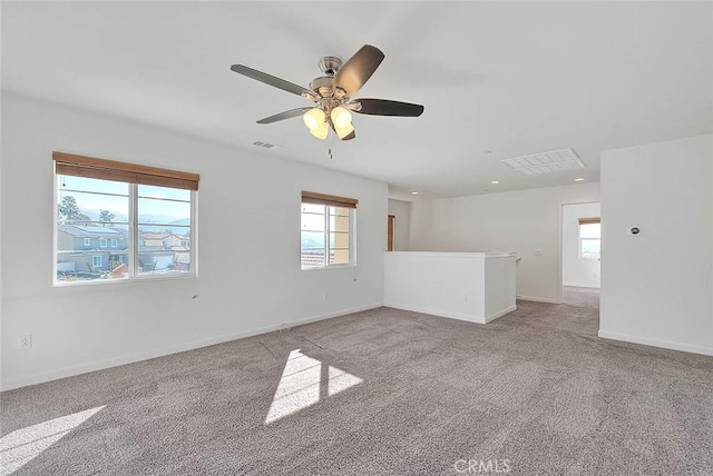 unfurnished room with a wealth of natural light, light colored carpet, and ceiling fan