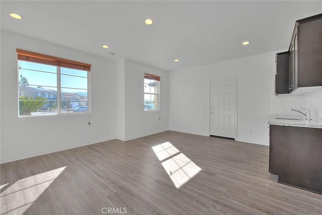 unfurnished living room featuring sink and light hardwood / wood-style floors