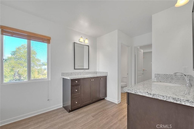 bathroom with hardwood / wood-style flooring, vanity, a healthy amount of sunlight, and toilet