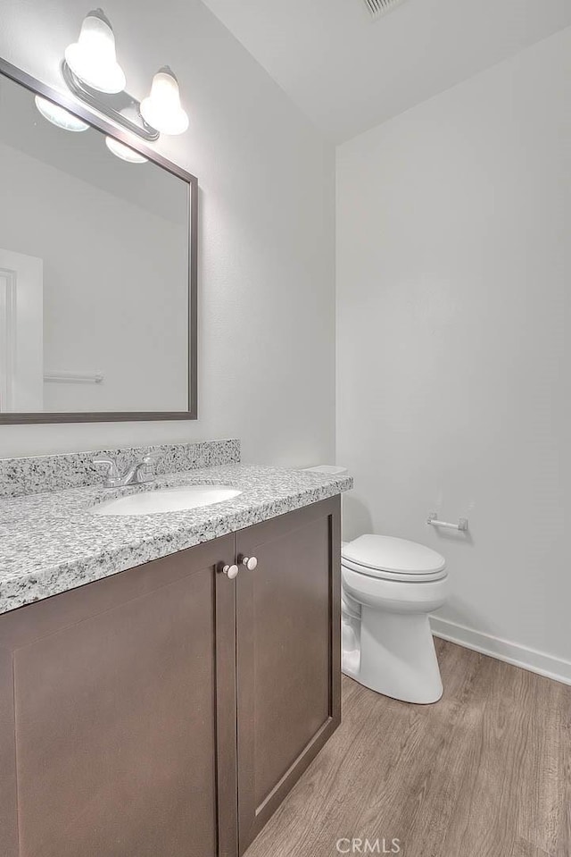 bathroom featuring vanity, wood-type flooring, and toilet