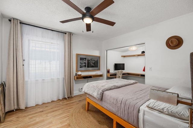 bedroom with ceiling fan, a textured ceiling, and light wood-type flooring