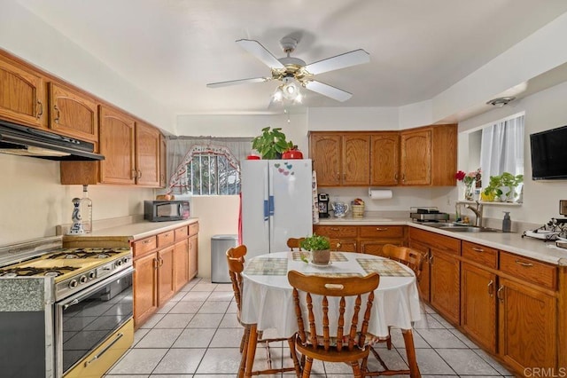 kitchen featuring sink, white fridge, light tile patterned floors, ceiling fan, and gas stove