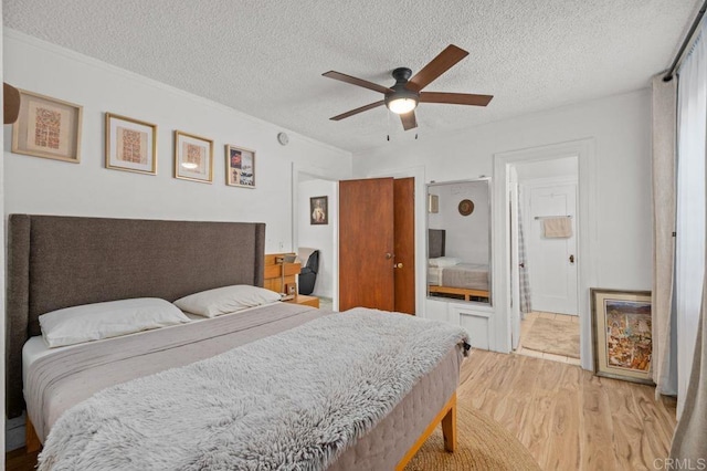 bedroom featuring ceiling fan, ensuite bath, a textured ceiling, and light wood-type flooring