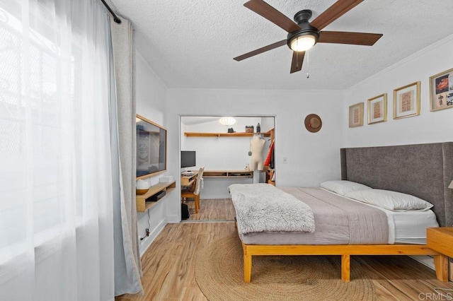 bedroom with a textured ceiling, light hardwood / wood-style flooring, a closet, and ceiling fan