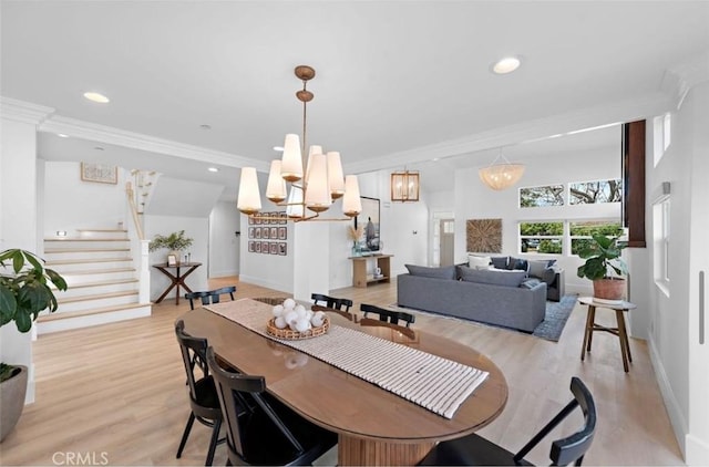 dining space with ornamental molding, a notable chandelier, and light hardwood / wood-style floors