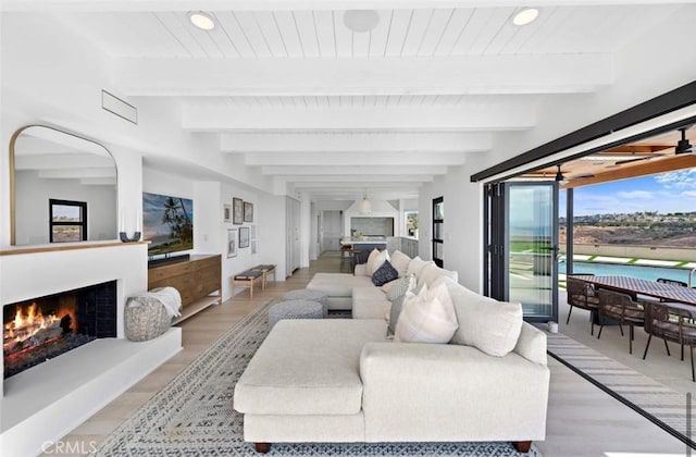 living room featuring beamed ceiling and light hardwood / wood-style flooring