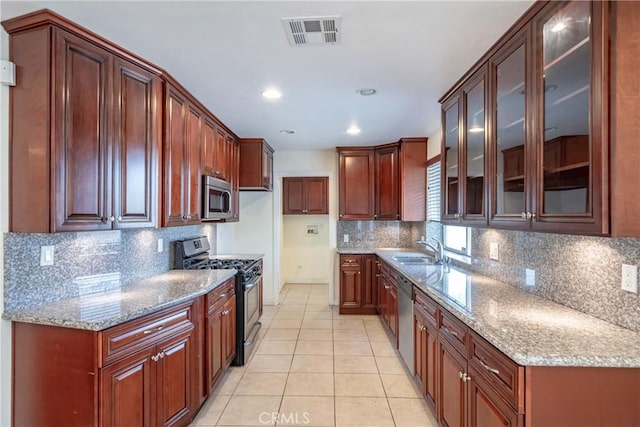 kitchen featuring sink, stainless steel appliances, light stone counters, light tile patterned flooring, and decorative backsplash