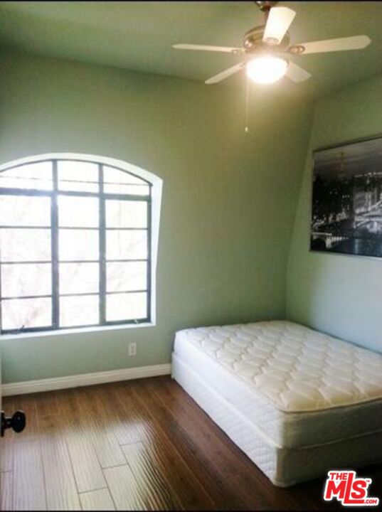 unfurnished bedroom featuring hardwood / wood-style floors and ceiling fan