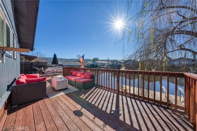 deck with an outdoor living space and a water view