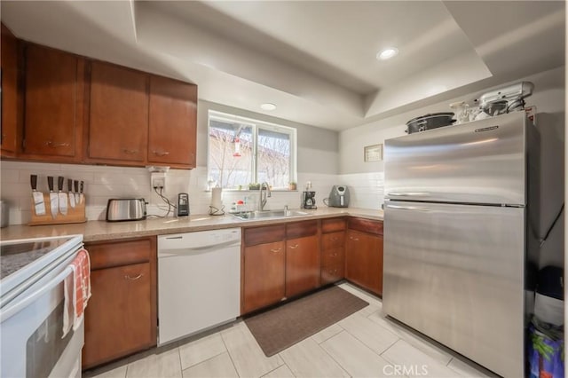 kitchen featuring tasteful backsplash, sink, light tile patterned floors, a raised ceiling, and white appliances