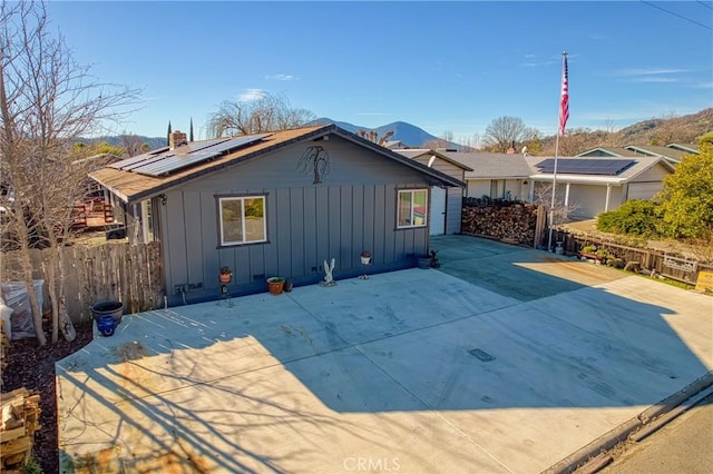 view of front of property with a patio, a mountain view, and solar panels