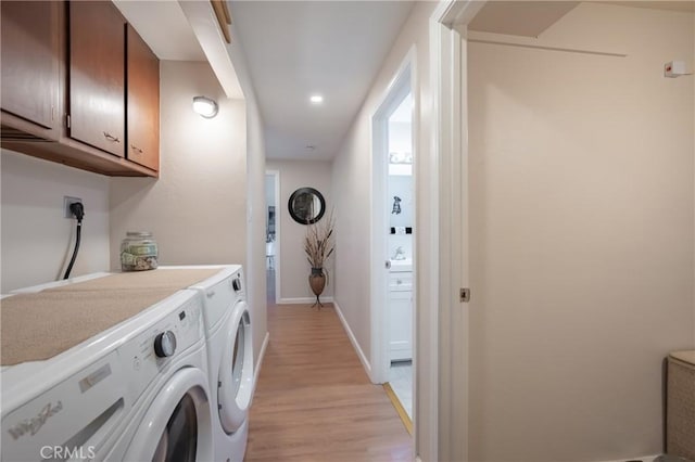 laundry room featuring cabinets, light hardwood / wood-style flooring, and washer and dryer