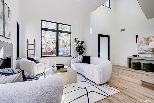 living room with light hardwood / wood-style floors and a high ceiling