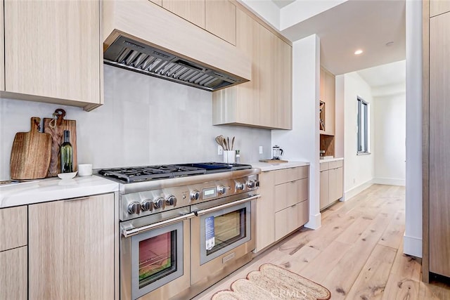 kitchen featuring light brown cabinetry, custom range hood, range with two ovens, and light hardwood / wood-style flooring