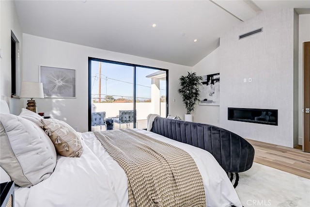 bedroom featuring access to outside, lofted ceiling with beams, and light wood-type flooring