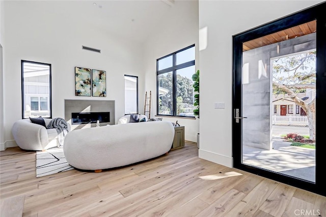 living room with light hardwood / wood-style flooring and a high ceiling