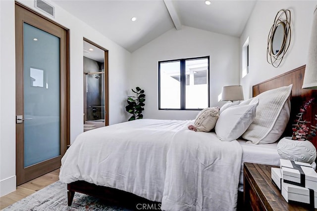 bedroom featuring ensuite bathroom, vaulted ceiling with beams, and light hardwood / wood-style flooring