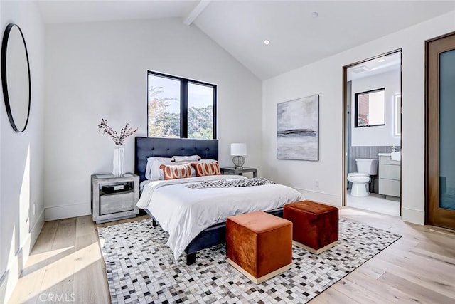 bedroom with vaulted ceiling with beams, ensuite bath, and light hardwood / wood-style flooring