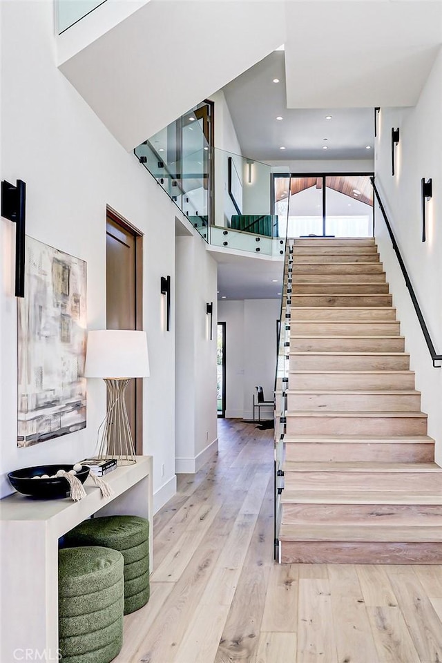 stairway with hardwood / wood-style floors, plenty of natural light, and a high ceiling