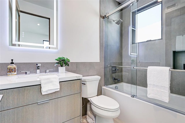 full bathroom featuring toilet, vanity, and bath / shower combo with glass door