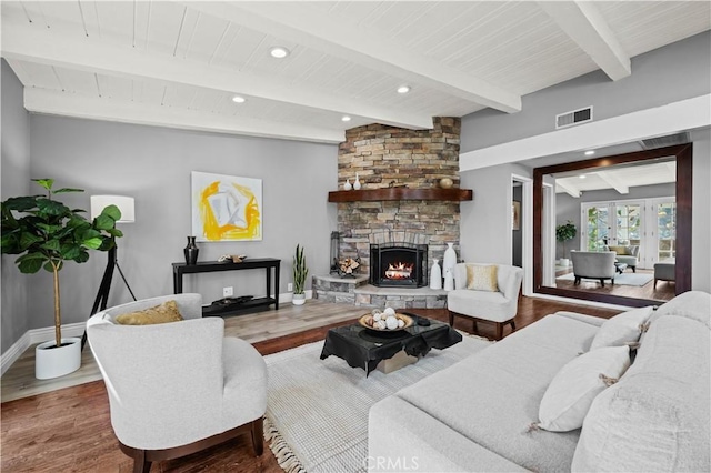 living room featuring beamed ceiling, a stone fireplace, hardwood / wood-style floors, and french doors