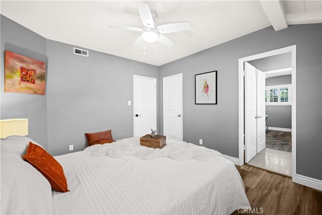 bedroom with lofted ceiling with beams, ceiling fan, hardwood / wood-style floors, and ensuite bath