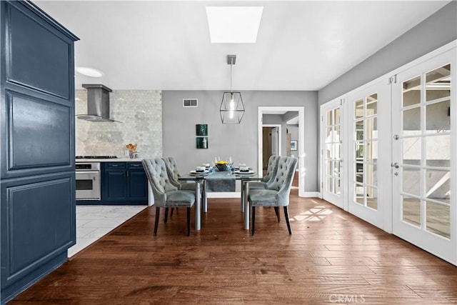 dining area with french doors, a skylight, and hardwood / wood-style flooring