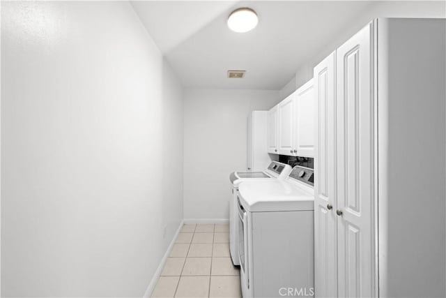 laundry area with cabinets, washing machine and dryer, and light tile patterned flooring