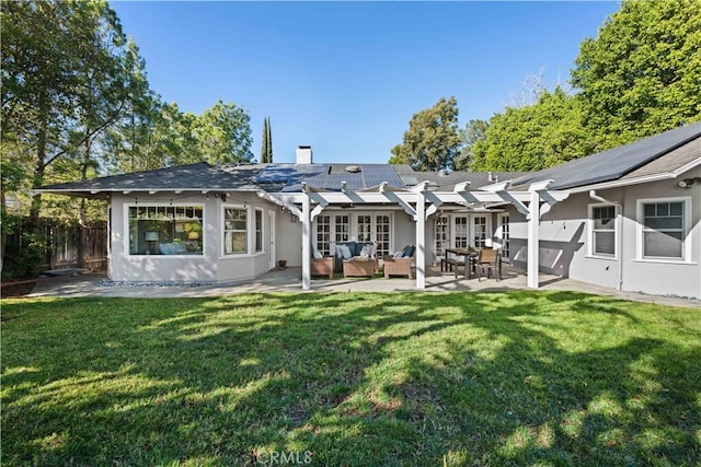 rear view of property with a lawn, a pergola, a patio, solar panels, and french doors