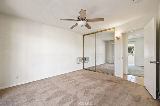 unfurnished bedroom with ceiling fan, a closet, and light carpet