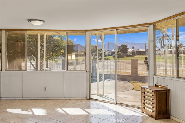 unfurnished sunroom featuring a healthy amount of sunlight, tile patterned floors, and a residential view