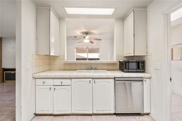 kitchen with appliances with stainless steel finishes, backsplash, a sink, and tile countertops