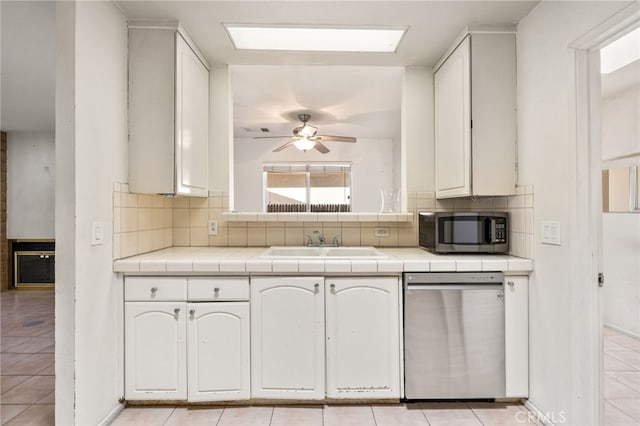 kitchen featuring ceiling fan, tile countertops, appliances with stainless steel finishes, tasteful backsplash, and a sink