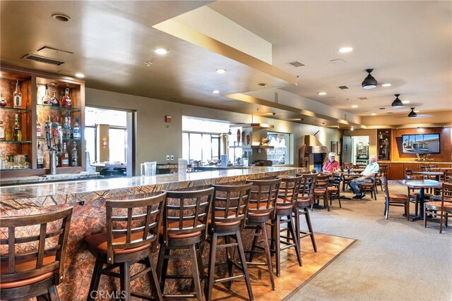 kitchen with a kitchen breakfast bar, ceiling fan, and carpet