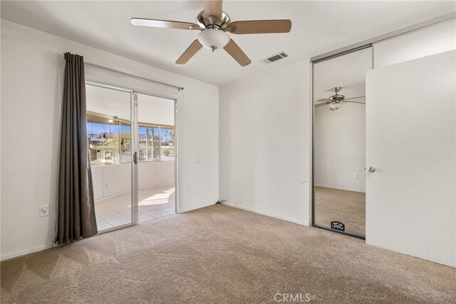 carpeted empty room featuring visible vents and ceiling fan