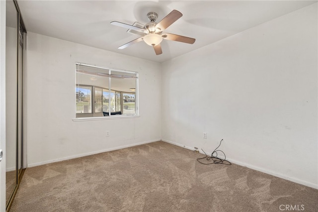 carpeted empty room with baseboards and a ceiling fan