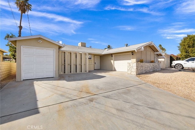 ranch-style house featuring an attached garage, fence, concrete driveway, and stucco siding