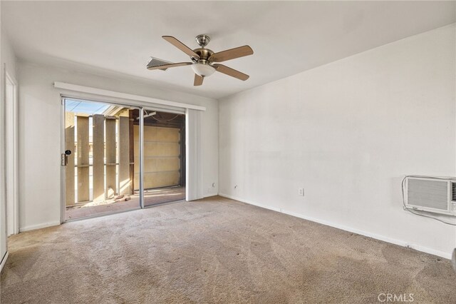 carpeted spare room featuring baseboards, visible vents, a ceiling fan, and an AC wall unit