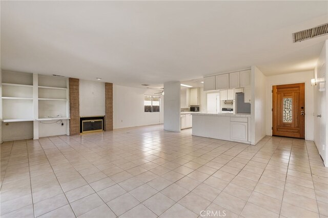 unfurnished living room with ceiling fan, a fireplace, and light tile patterned floors