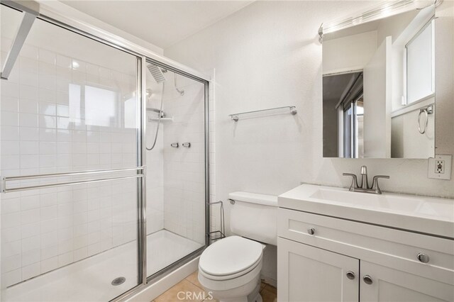 bathroom with tile patterned floors, toilet, a shower with shower door, and vanity