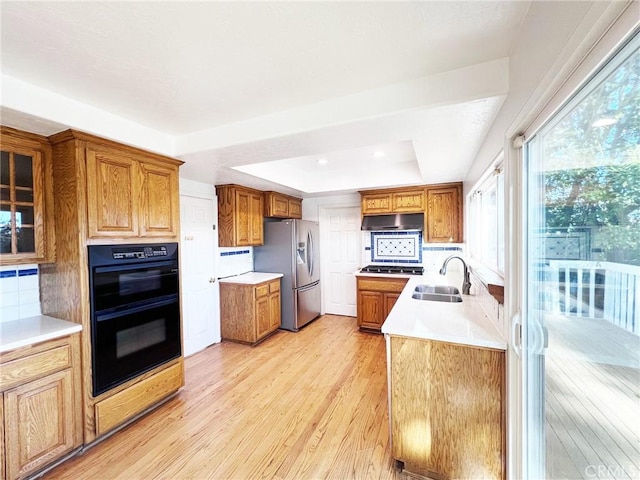 kitchen with sink, light hardwood / wood-style flooring, stainless steel appliances, decorative backsplash, and a raised ceiling